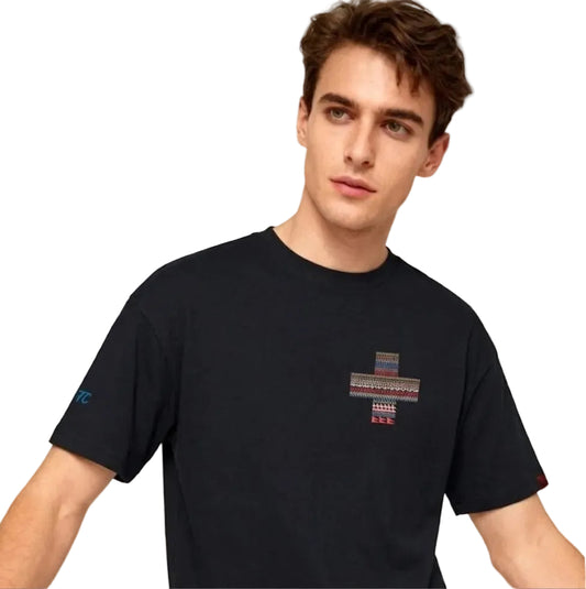 Man wearing a black t-shirt with a colorful geometric design on a plain background